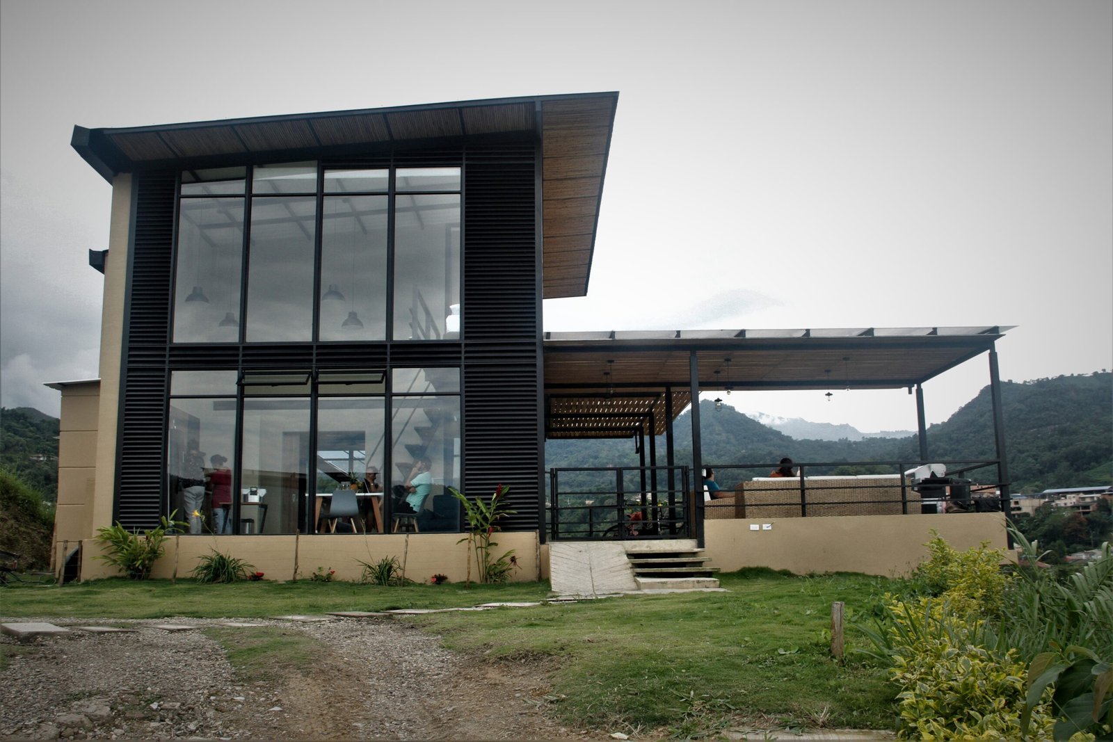 Fachada de la casa campestre en Sasaima, con grandes ventanales y terraza cubierta