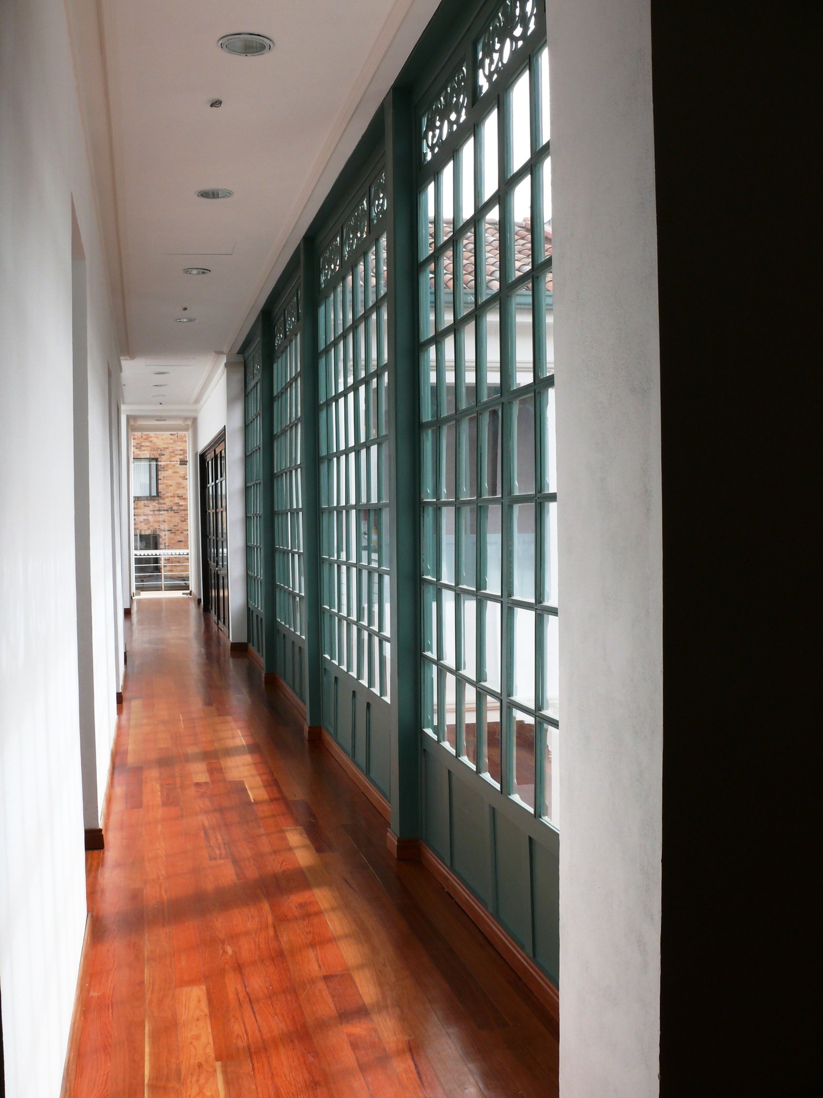 Corredor restaurado con mampara verde y piso de madera