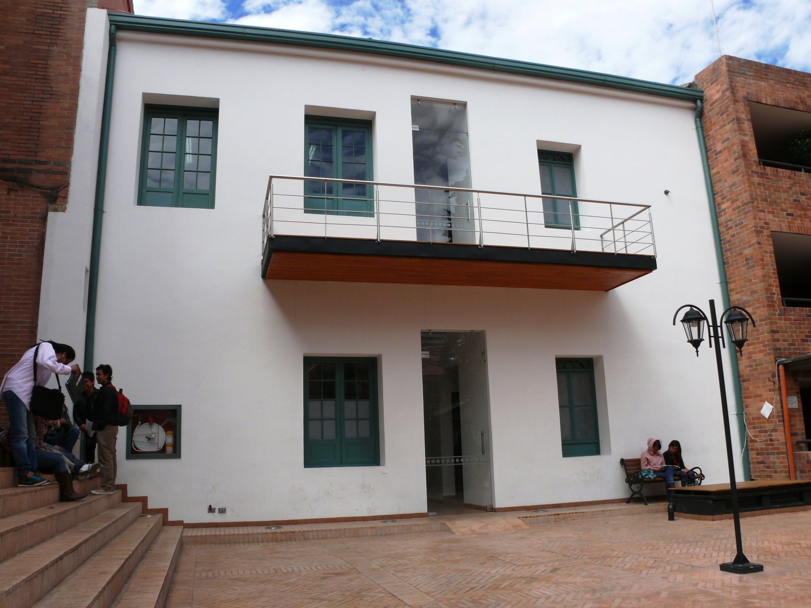 Patio interior restaurado con balcón y carpinterías verdes